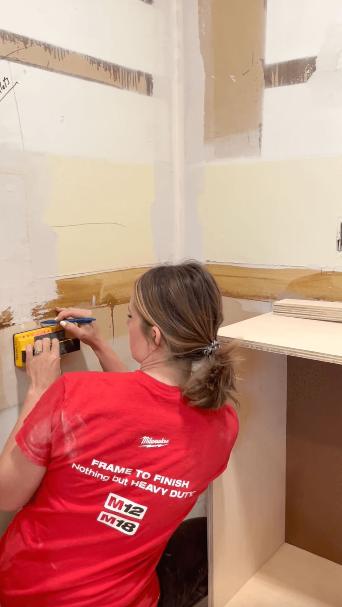 Using a stud finder to mark wall studs.